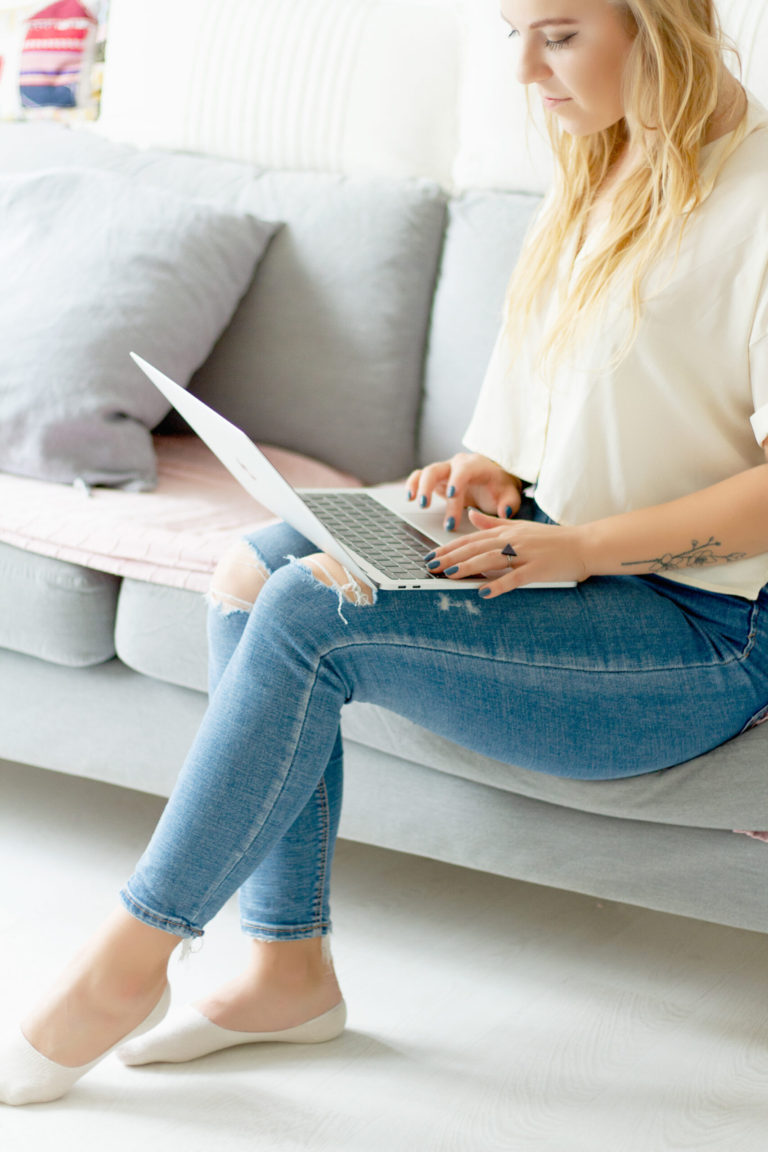 woman in jeans typing on laptop